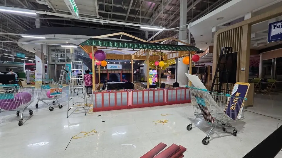 ทีมช่างกำลังตกแต่งซุ้มบาร์ทรงเกาหลีพร้อมโคมไฟระหว่างติดตั้ง